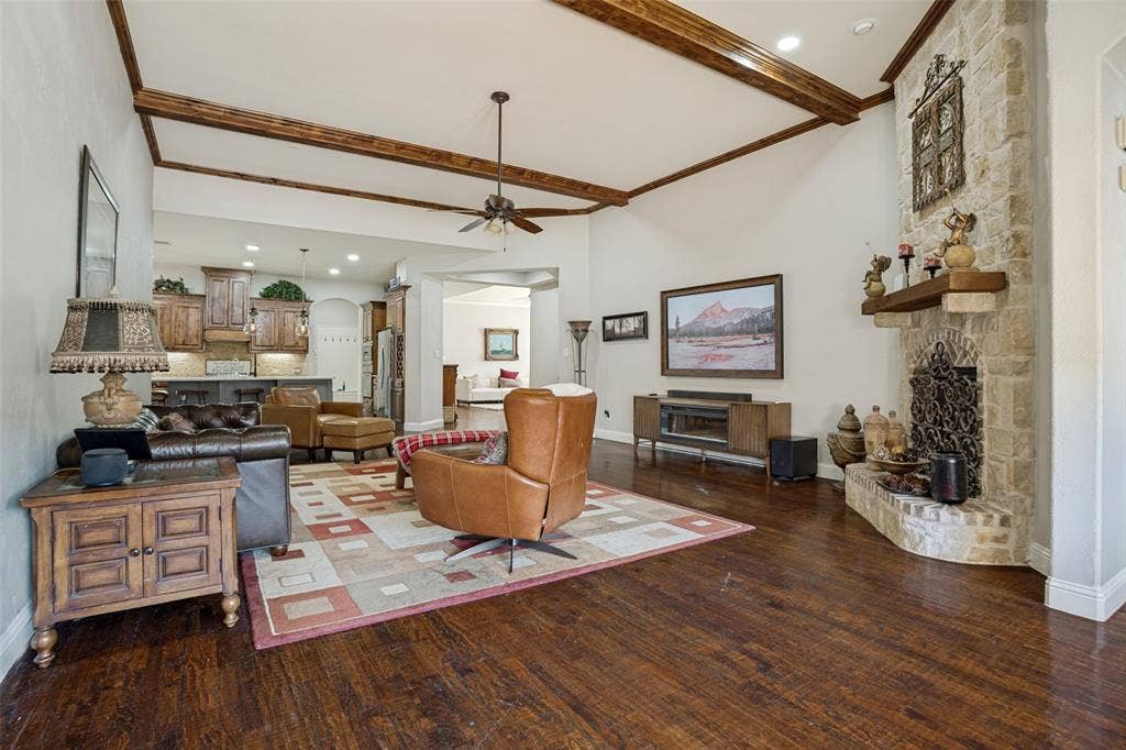 1250 Packsaddle Trail, Prosper, TX 75078 Vaulted ceiling with exposed wood beams, stone-clad fireplace with hearth, dark wood-finish flooring, and recessed lighting