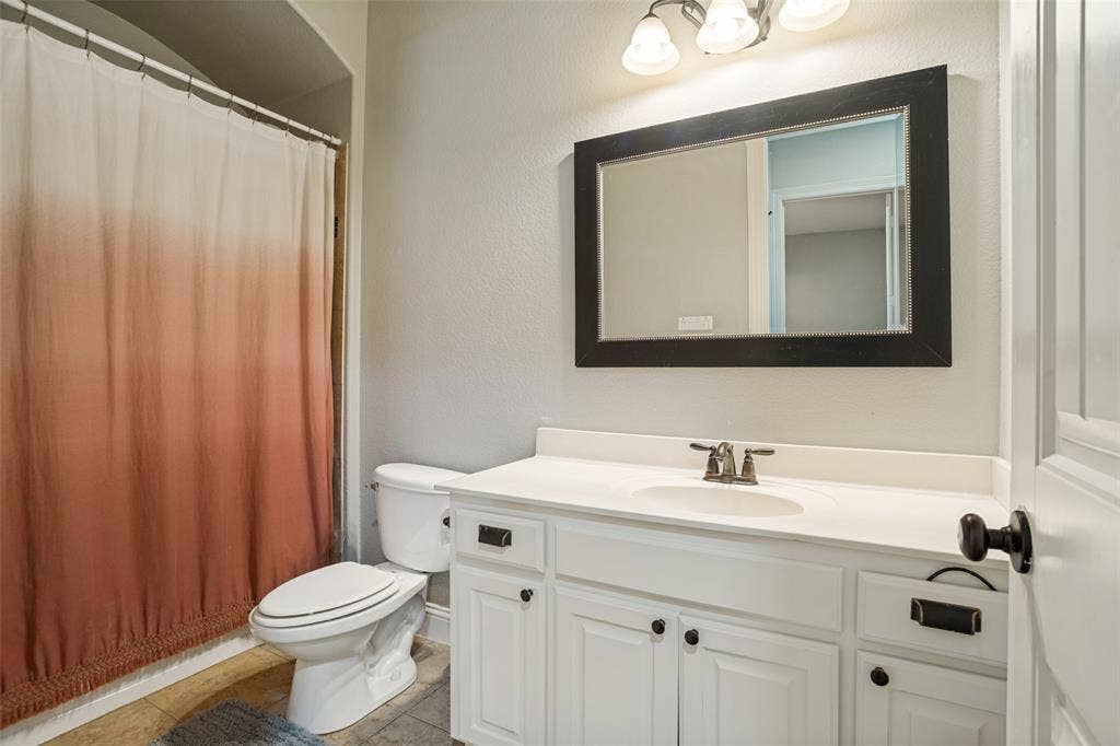 1250 Packsaddle Trail, Prosper, TX 75078 White cabinetry with black hardware, white countertop, framed mirror, and integrated sink