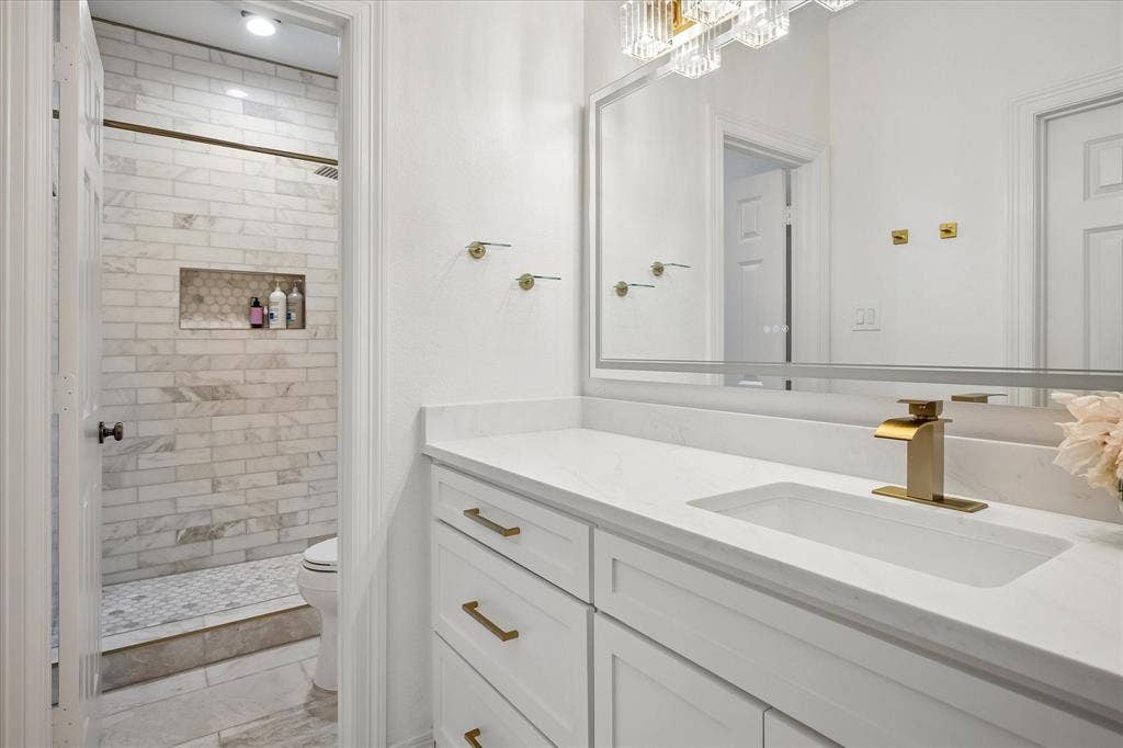 2916 Thomas Avenue, Dallas, TX 75204 Spa-inspired primary bathroom featuring a floating vanity with dual sinks, white quartz countertop, and brass fixtures