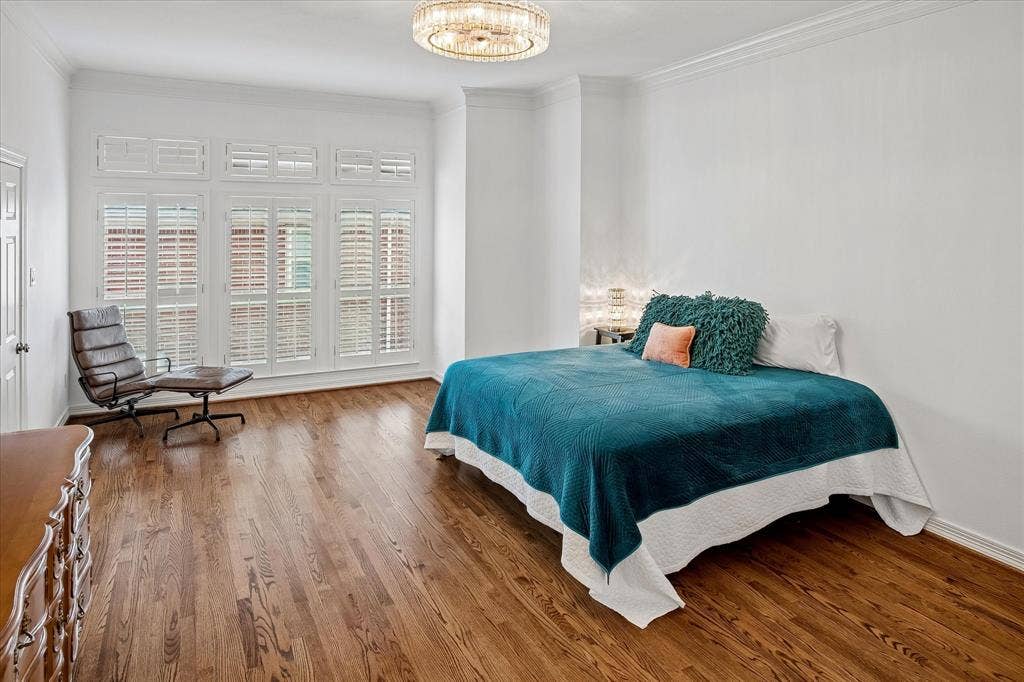 2916 Thomas Avenue, Dallas, TX 75204 Hardwood flooring, crown molding, white walls, multiple windows with white plantation shutters, and a chandelier with a crystal-style shade