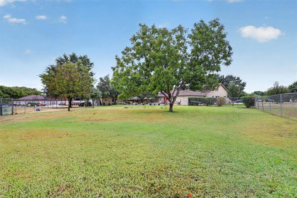 Expansive green space featuring established trees and perimeter fencing