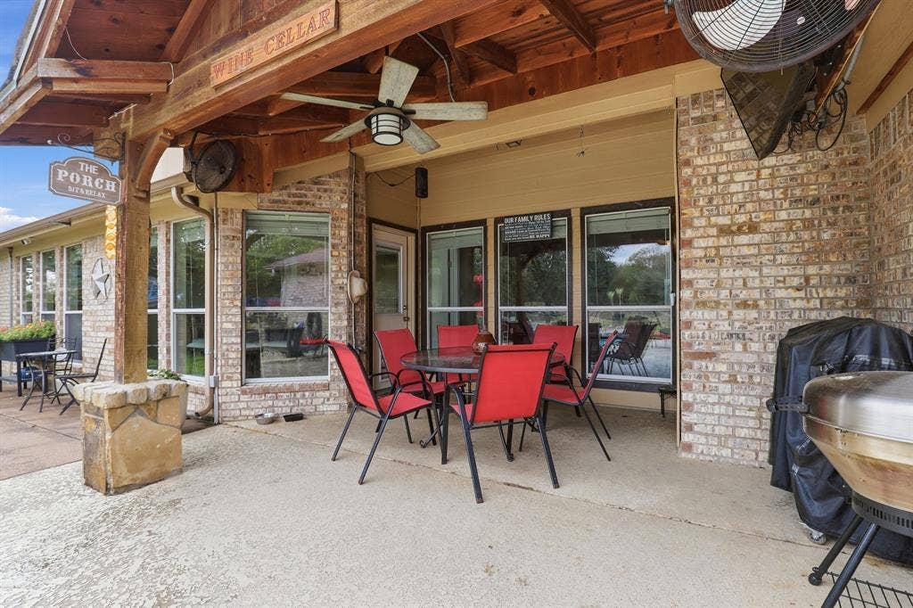 Covered concrete patio with a wood-finish ceiling, exposed brick exterior, and multiple windows