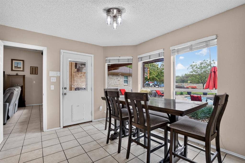 Bay window with multiple large windows, recessed ceiling light fixture, white tile flooring, and direct outdoor access