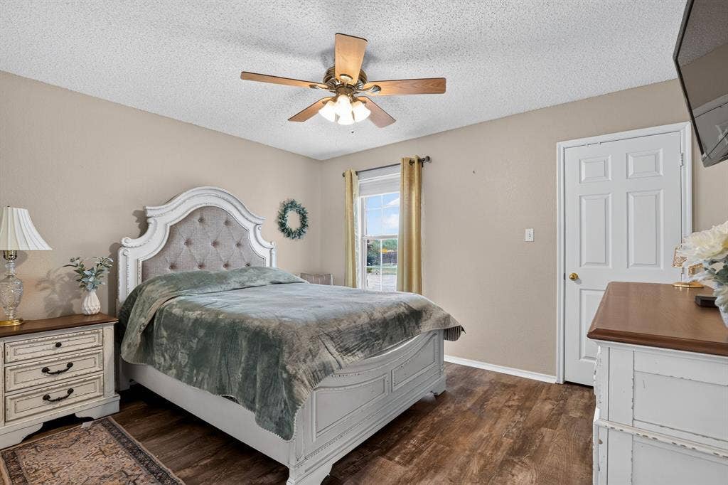 Wood-finish flooring, ceiling fan with integrated lighting, and a window with curtain rods