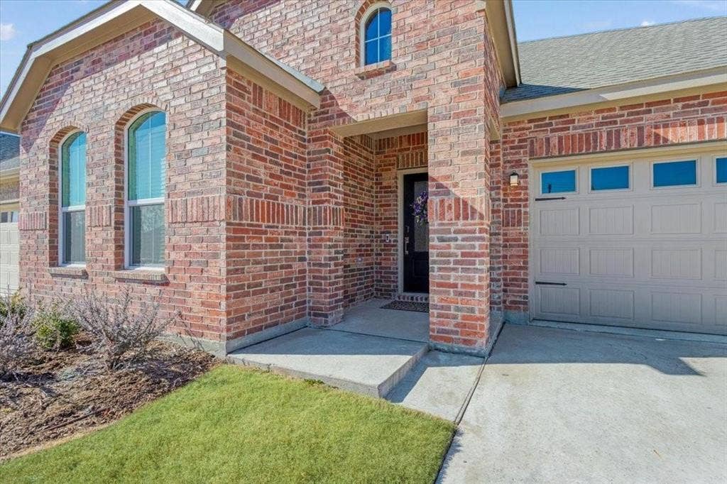 Brick exterior with arched windows, covered entry, and attached garage