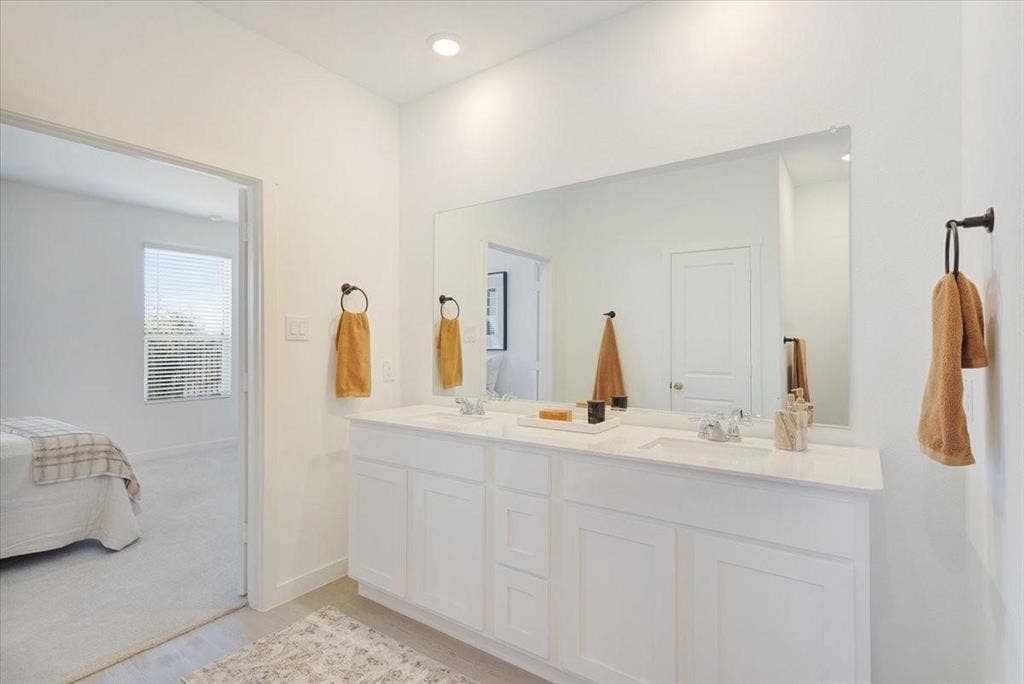 Double vanity with dual sinks, a stone countertop, and a large wall-mounted mirror