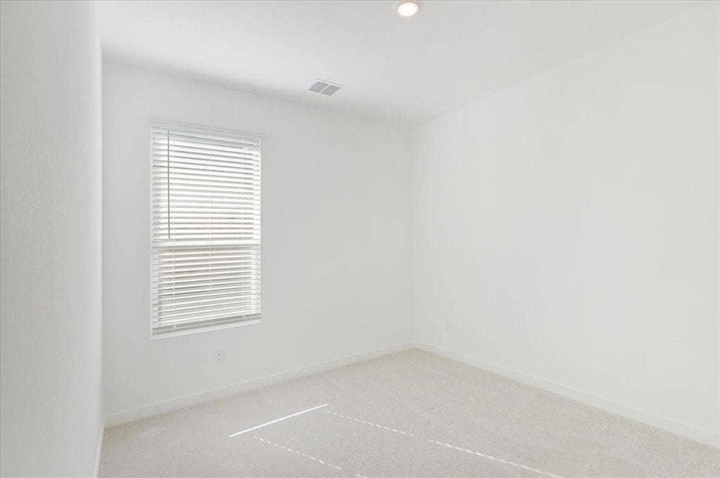 Recessed lighting, window with blinds, light-colored carpeting, white walls