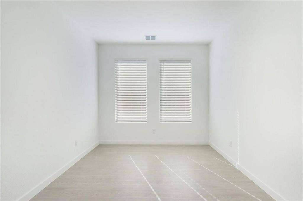 Crisp white walls, two windows with blinds, wood-finish flooring, and recessed lighting