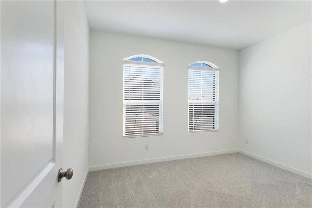 Arched windows with blinds, recessed lighting, and light-toned carpet flooring