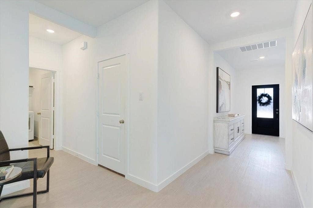 Hallway featuring recessed lighting, light wood-finish flooring, white walls, a white two-panel interior door, and a black front door with an integrated window