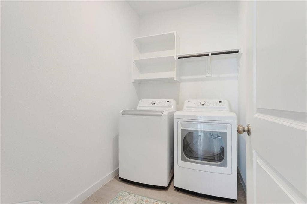 Integrated laundry area featuring built-in shelving, a clothes hanging rod, and light-toned flooring