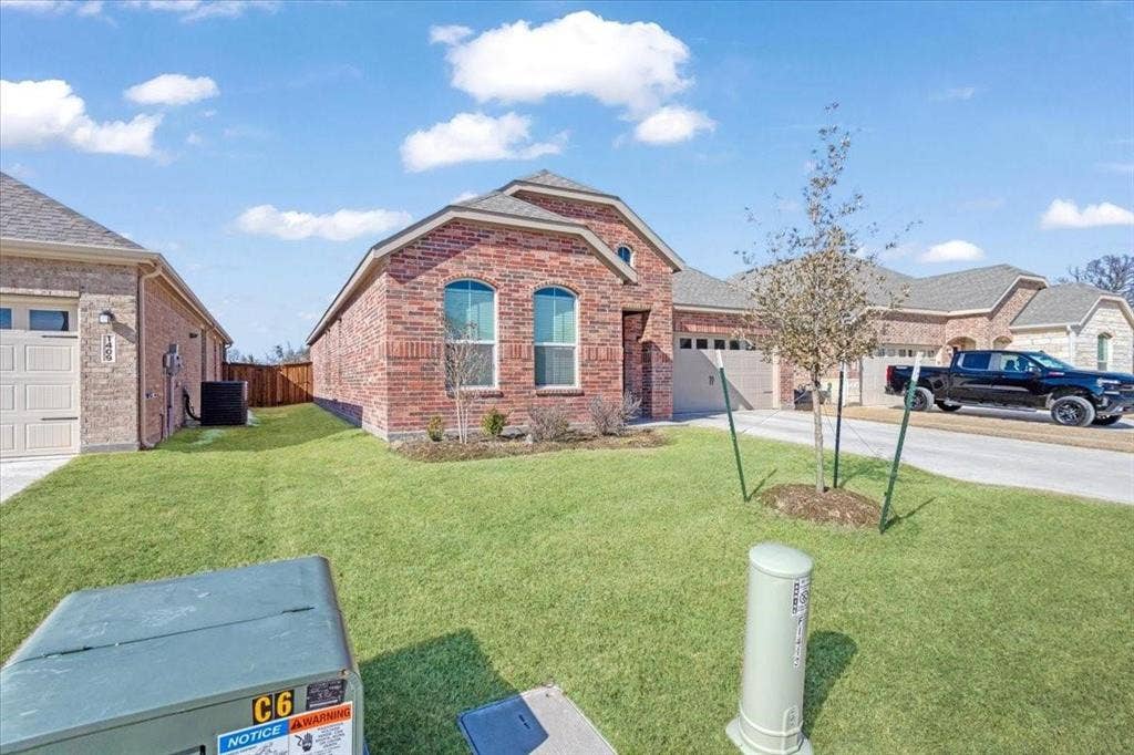 Brick exterior with arched windows, attached garage, and a well-maintained lawn