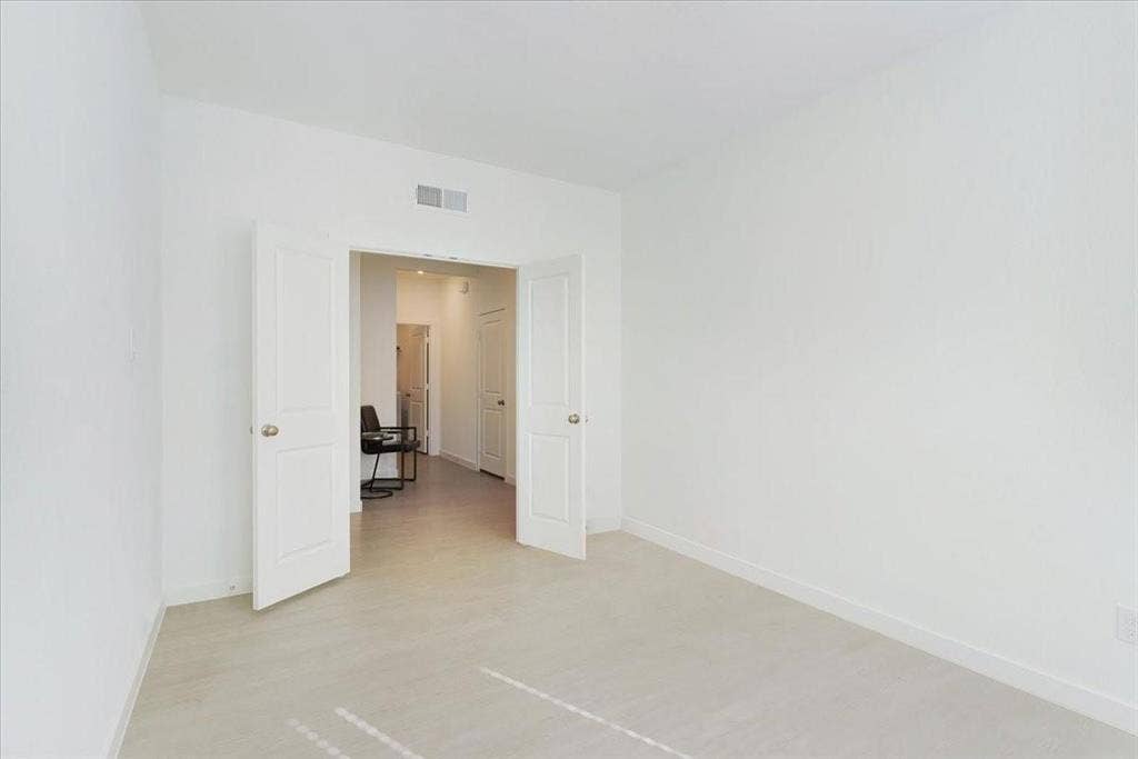 Dual paneled doors opening to a light-toned corridor