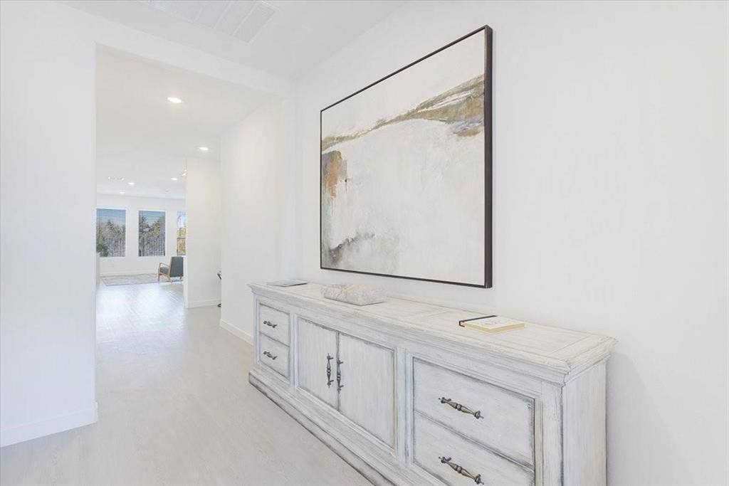 White walls with recessed lighting and light-toned wood-finish flooring