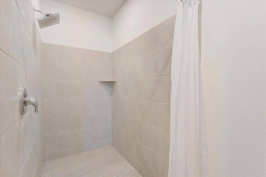 Tiled shower surround with a built-in corner shelf, chrome showerhead, and coordinating chrome faucet