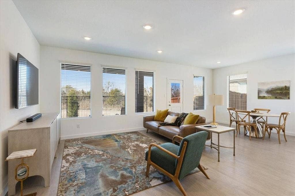 Open-concept living area with light-toned wood-finish flooring, recessed lighting, and multiple windows