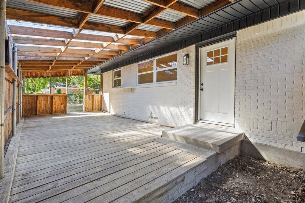 917 Blossom Circle, Garland, TX 75041 Expansive covered patio with exposed wood beams and a corrugated roof