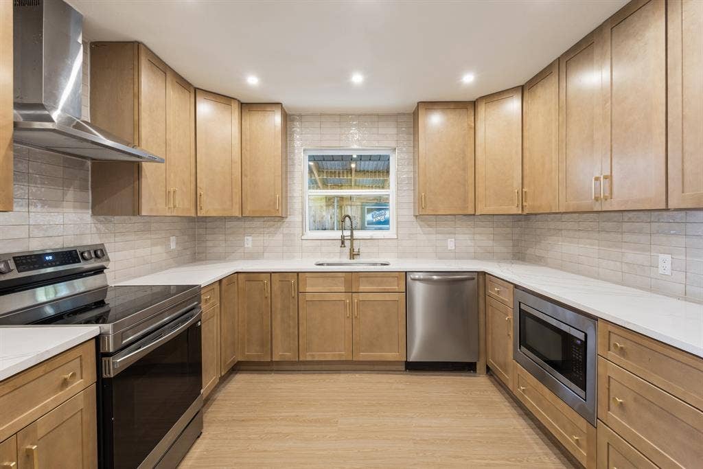 917 Blossom Circle, Garland, TX 75041 U-shaped kitchen featuring stainless steel Electric Range and powerful exhaust outside and a full-height tile backsplash
