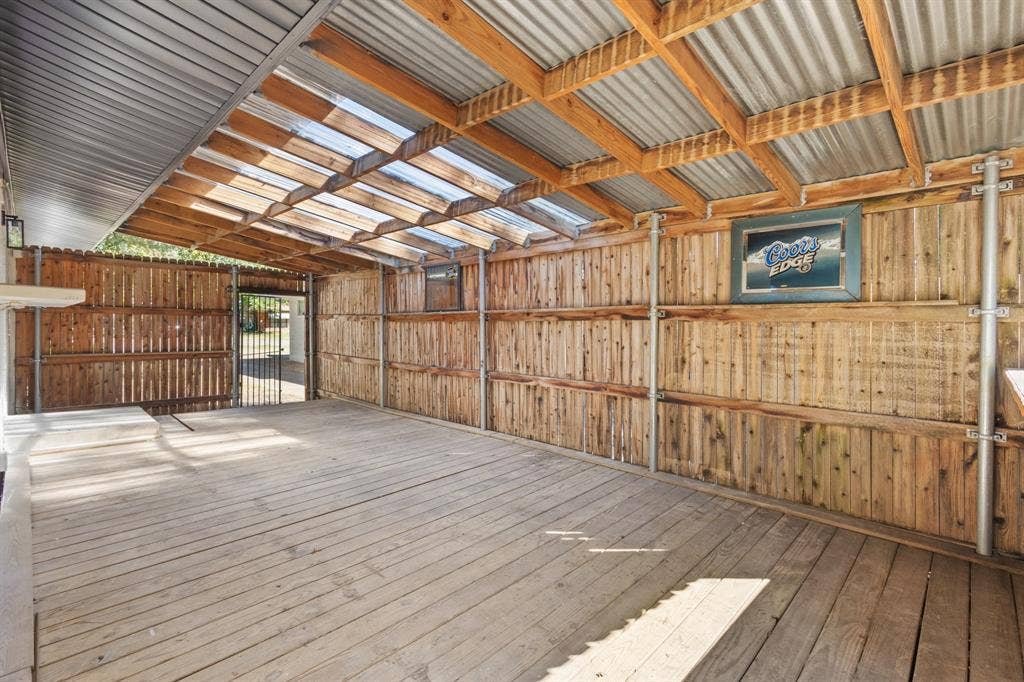 917 Blossom Circle, Garland, TX 75041 Expansive covered outdoor area featuring wood decking, a corrugated metal and clear panel roof, and natural wood plank walls, excellent for outdoor dining and activities