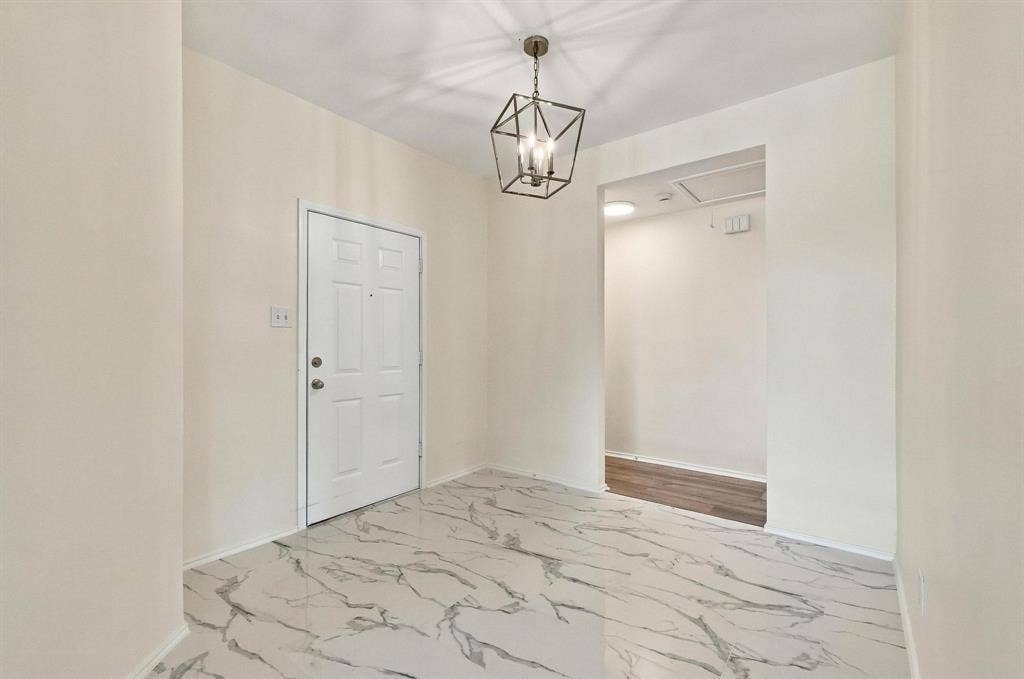 Entryway featuring marbled floor tiles, a decorative geometric chandelier, and a paneled entry door
