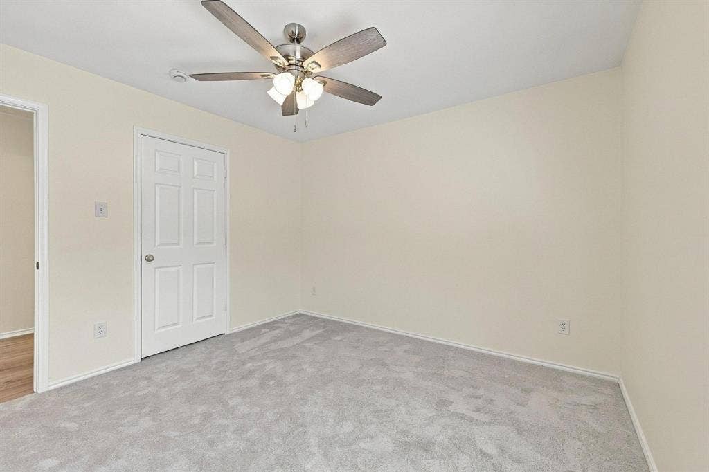 Neutral wall color, ceiling fan with light fixture, light gray carpeting, paneled interior door, and white trim