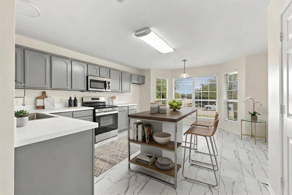 This room has been virtually staged using AI to illustrate its potential countertops, stainless steel appliances, grey cabinetry, white tile flooring, and a central island with open shelving