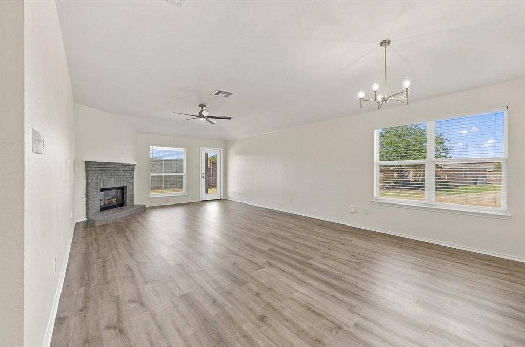 Spacious living area featuring wood-finish flooring, a contemporary chandelier, and a ceiling fan