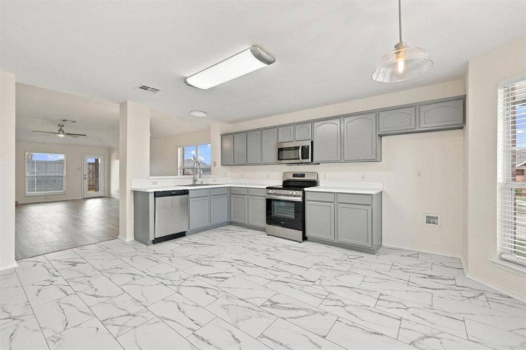 Kitchen featuring L-shaped gray cabinetry, stainless steel appliances, a stainless steel sink, and white countertops