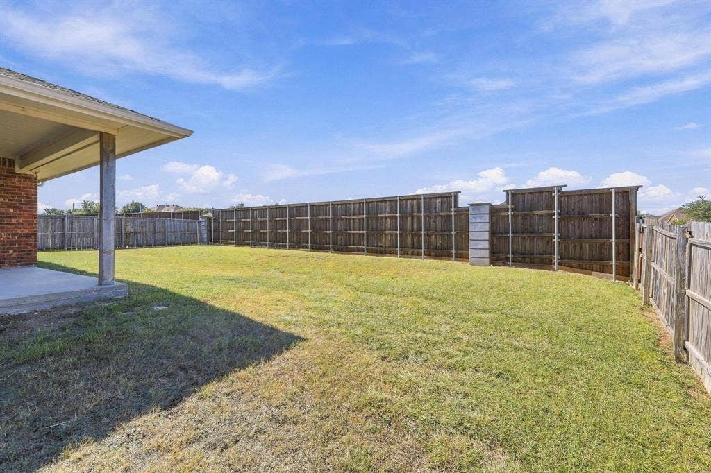 Expansive grassy yard with wood privacy fencing and an exterior patio