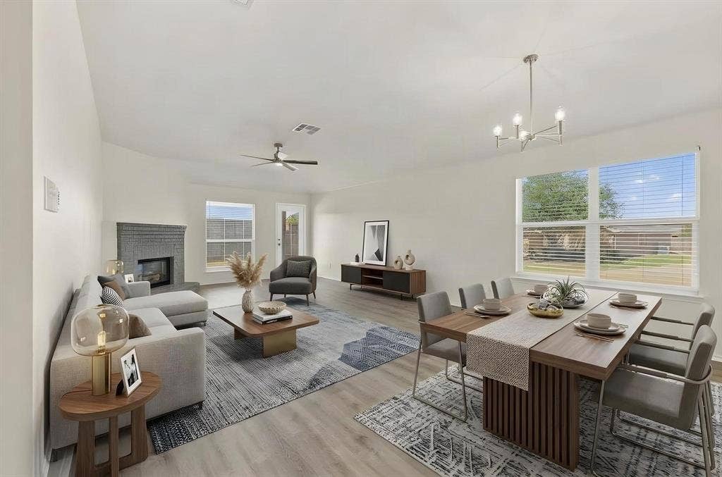 This room has been virtually staged using AI to illustrate its potential-concept living and dining area featuring wood-finish flooring, a fireplace with a stone surround, a contemporary ceiling fan, and a modern chandelier