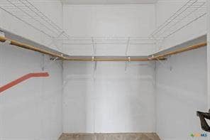 Walk-in closet featuring wire shelving, multiple wooden hanging rods, and light-colored walls