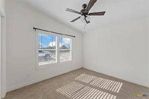 Vaulted ceiling, two large windows, ceiling fan with light fixture, and carpeted flooring
