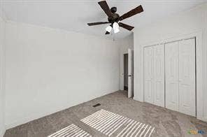 Neutral wall color, carpet flooring, ceiling fan with light fixture, and bifold closet doors