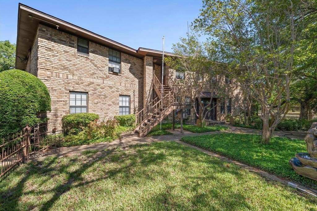 4201 N 19th Street, Waco, TX 76708 Brick exterior construction, multiple windows, exterior staircase, landscaped grounds, and a decorative water feature