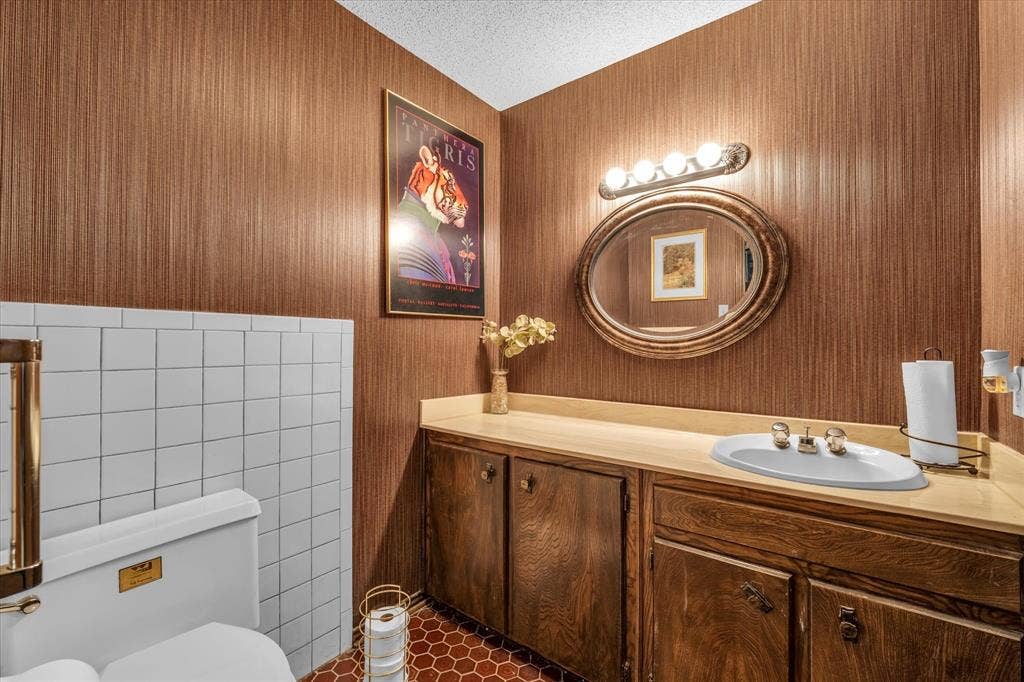 4201 N 19th Street, Waco, TX 76708 Vanity with wood-finish cabinetry, a built-in sink, and an oval mirror
