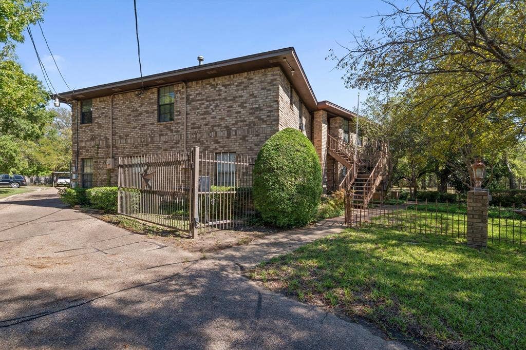 4201 N 19th Street, Waco, TX 76708 Brick exterior with multiple windows, featuring a wrought iron fence with a decorative gate