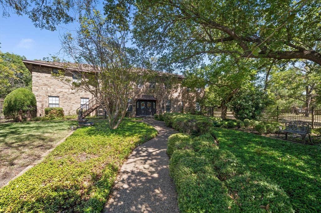 4201 N 19th Street, Waco, TX 76708 Brick exterior with a gabled roofline, featuring a stone-paved walkway, mature trees, and manicured landscaping