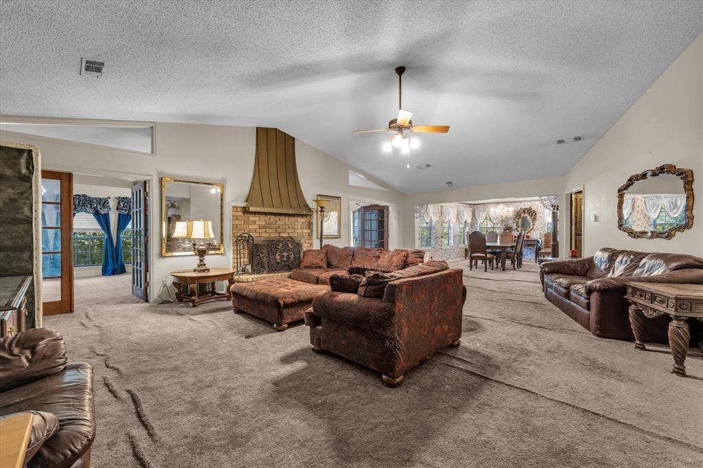 4201 N 19th Street, Waco, TX 76708 Spacious living area featuring a brick fireplace with a custom metal hood, vaulted ceilings, and a ceiling fan