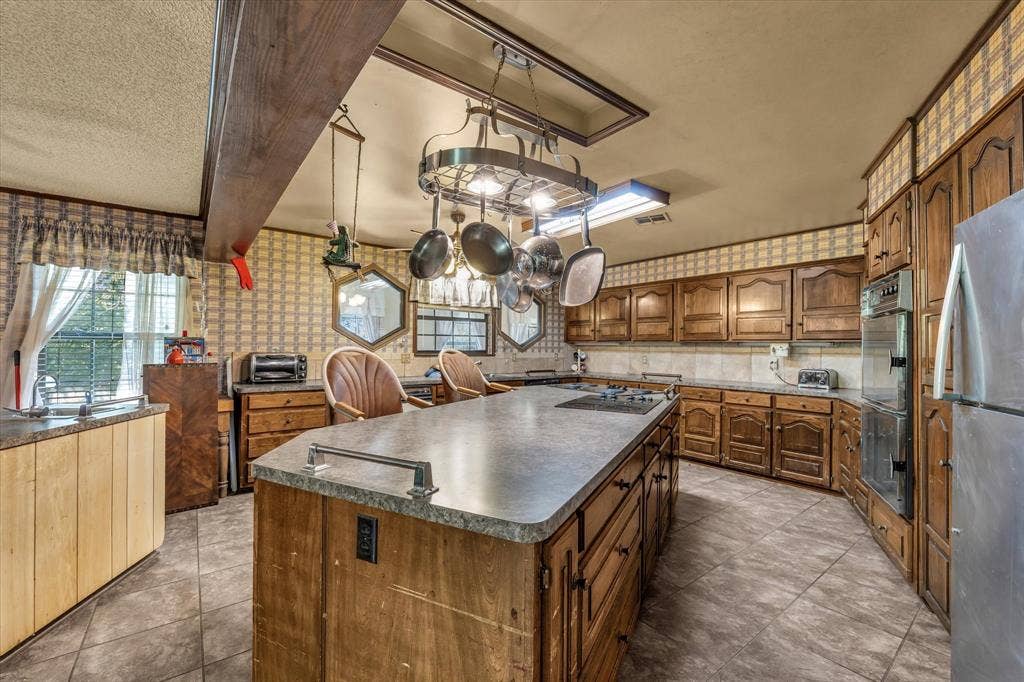 4201 N 19th Street, Waco, TX 76708 Spacious kitchen with a large central island, integrated cooktop, wood cabinetry, and a pot rack