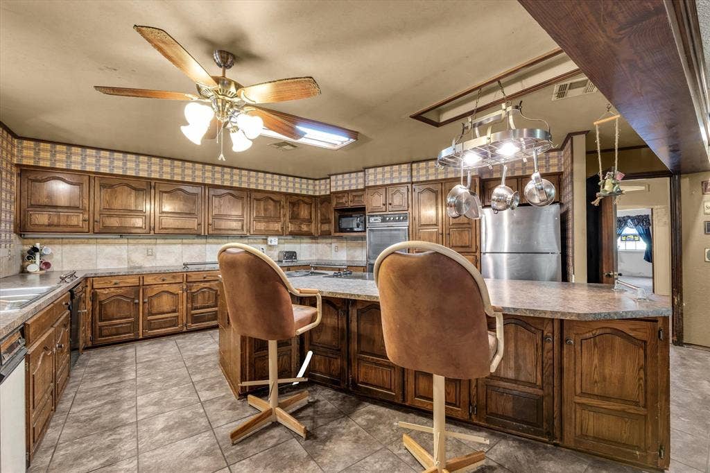 4201 N 19th Street, Waco, TX 76708 Kitchen featuring wood cabinetry, tile flooring, stone-finish countertops, and a ceiling fan with integrated lighting