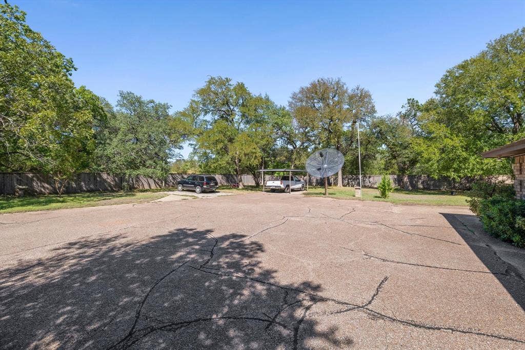 4201 N 19th Street, Waco, TX 76708 Paved surface, mature trees, partial fencing, and a covered parking structure