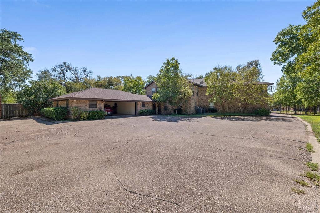 4201 N 19th Street, Waco, TX 76708 Extensive paved parking area with brick exterior structures, mature trees, and landscaping