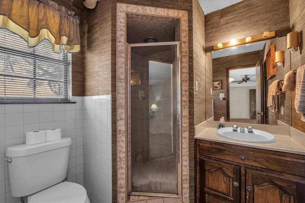 4201 N 19th Street, Waco, TX 76708 Bathroom featuring white ceramic wall tile, an enclosed shower, a single vanity with an integrated sink, and an overhead light bar