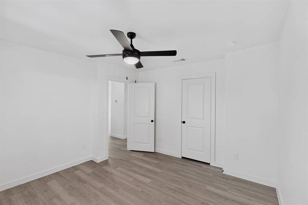 651 Ezekial Avenue, Dallas, TX 75217 Wood-finish flooring, white walls, black ceiling fan with integrated lighting, and white doors with black hardware