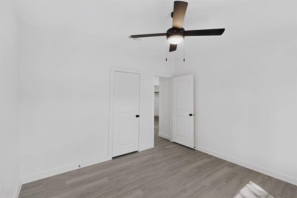 651 Ezekial Avenue, Dallas, TX 75217 Bright corner bedroom with wood-finish flooring, dual white panel doors, and ceiling-mounted fan with integrated lighting fixture