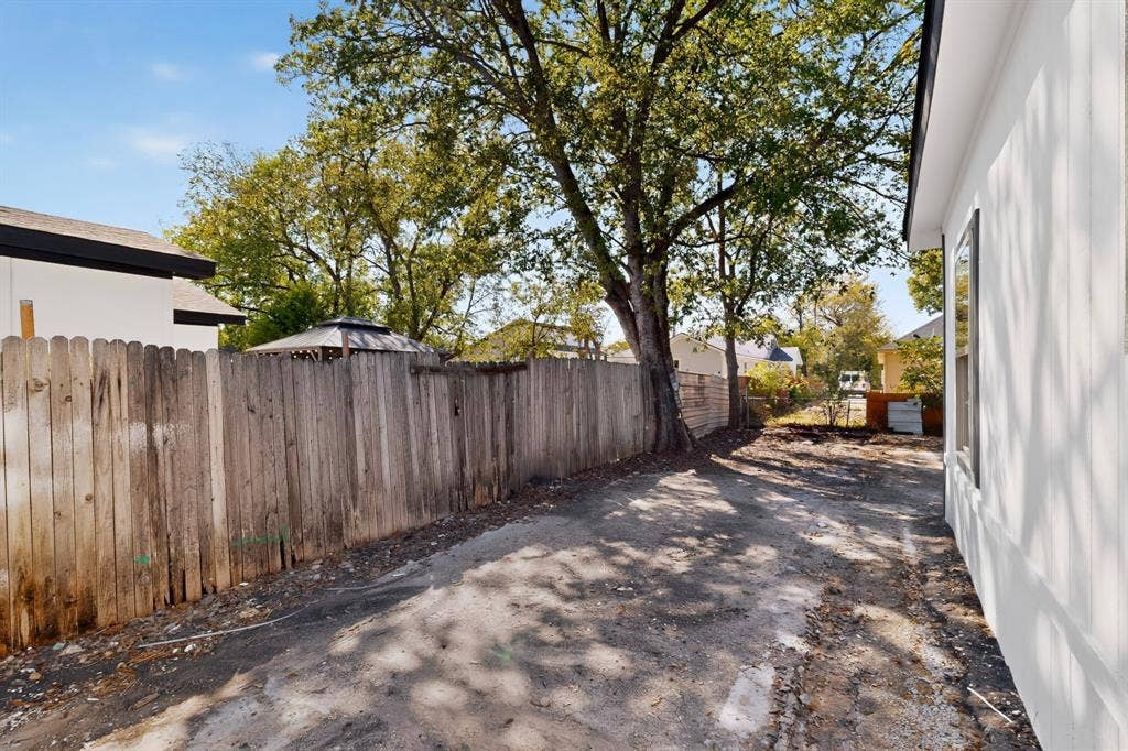 651 Ezekial Avenue, Dallas, TX 75217 Side yard with a wood-plank privacy fence and mature tree
