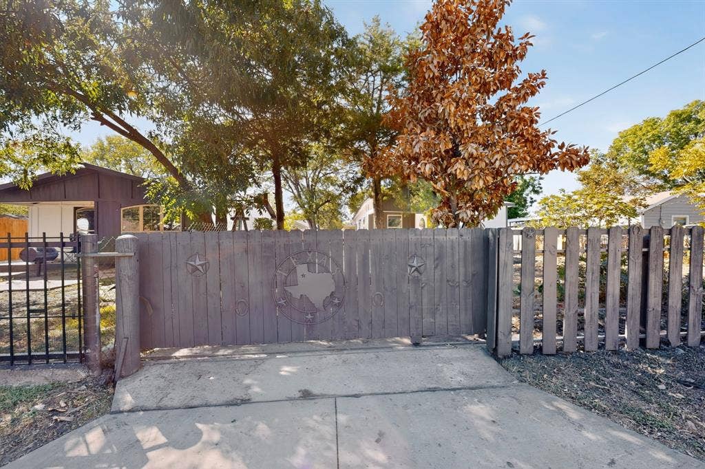 651 Ezekial Avenue, Dallas, TX 75217 Wood-panel fencing with decorative metal accents and an adjacent metal gate