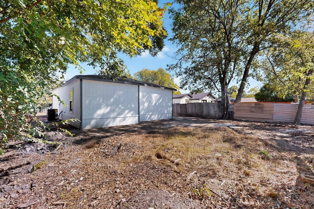 651 Ezekial Avenue, Dallas, TX 75217 Expansive outdoor space featuring a white siding exterior, mature trees, and a wood privacy fence