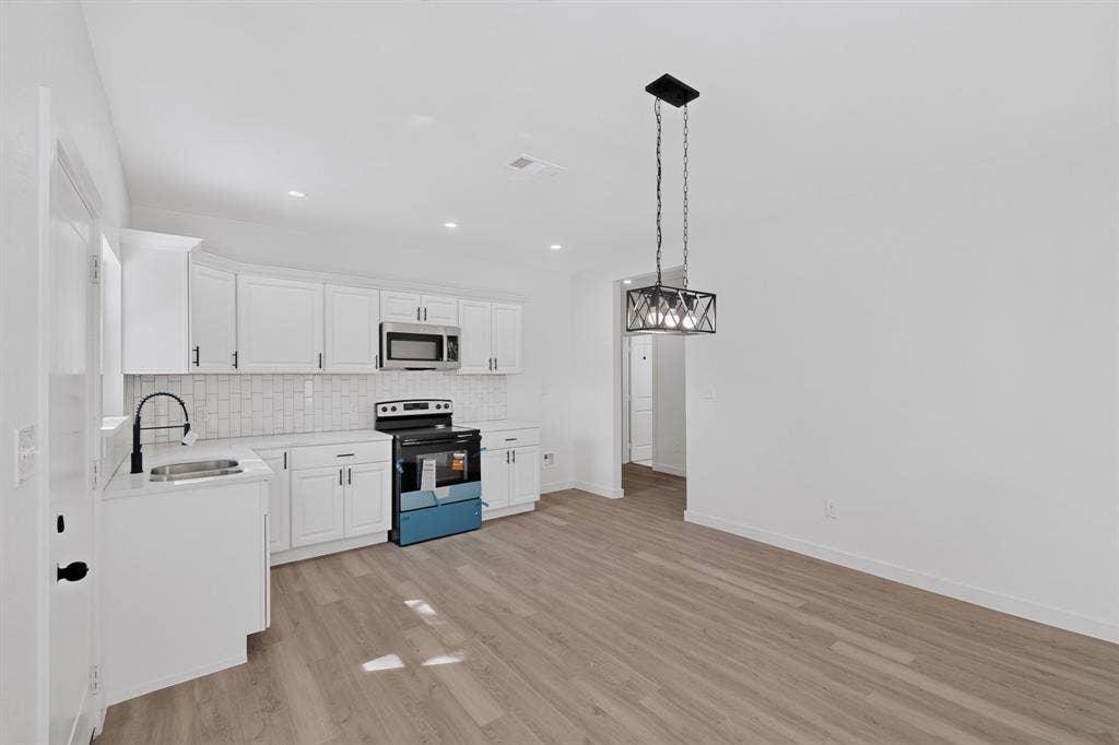 651 Ezekial Avenue, Dallas, TX 75217 Contemporary kitchen with white cabinetry, stainless steel microwave, and a subway tile backsplash
