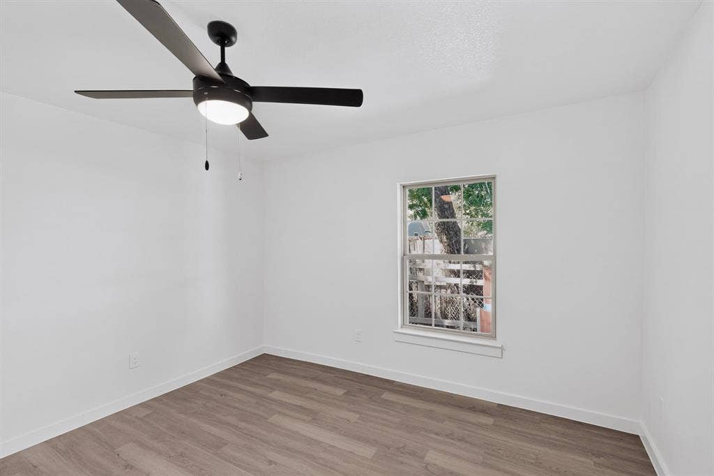 651 Ezekial Avenue, Dallas, TX 75217 Wood-finish flooring, white painted walls, single window with white trim, and a black ceiling fan with integrated lighting